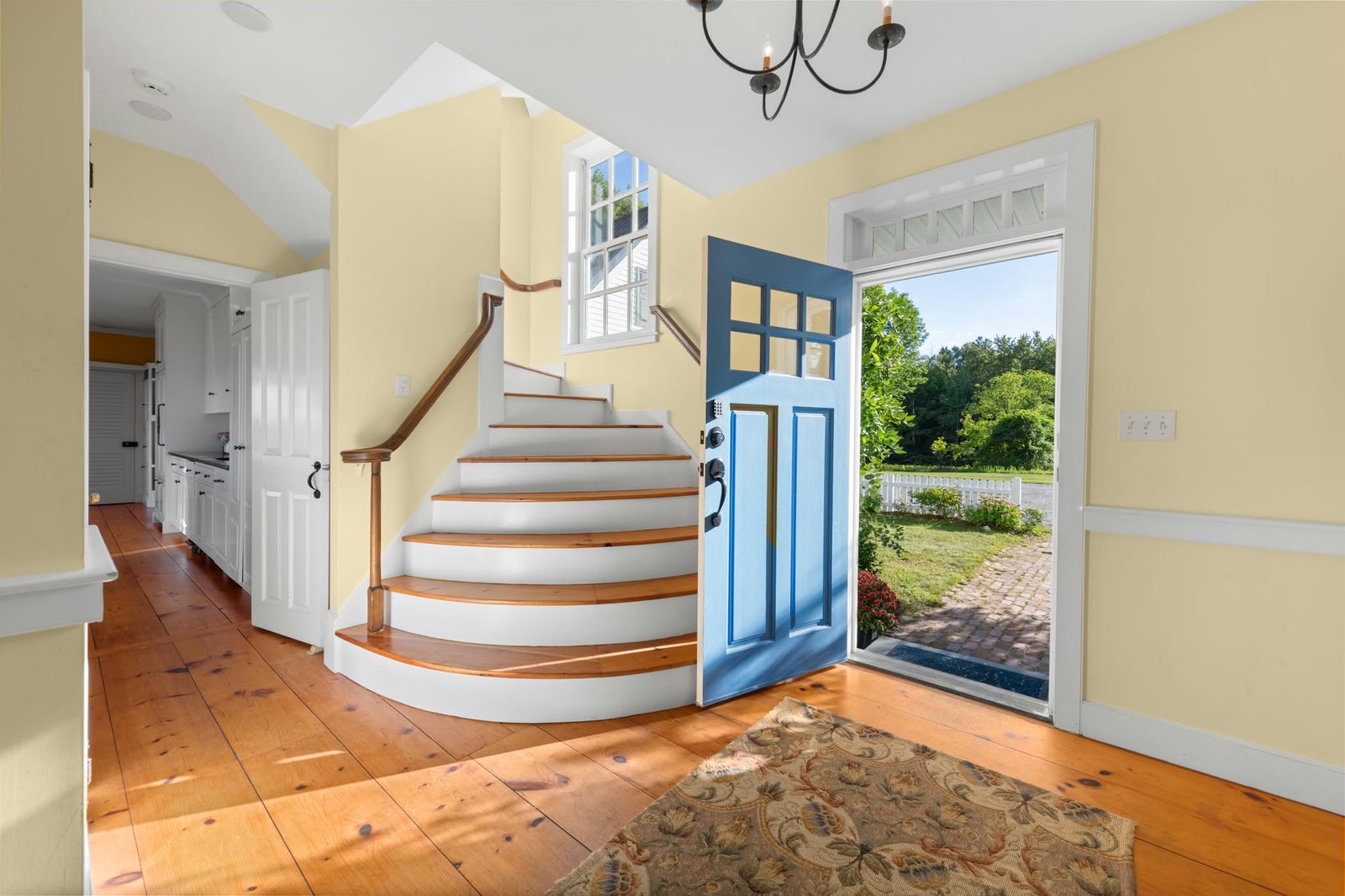 Bright entryway with a white staircase and blue front door