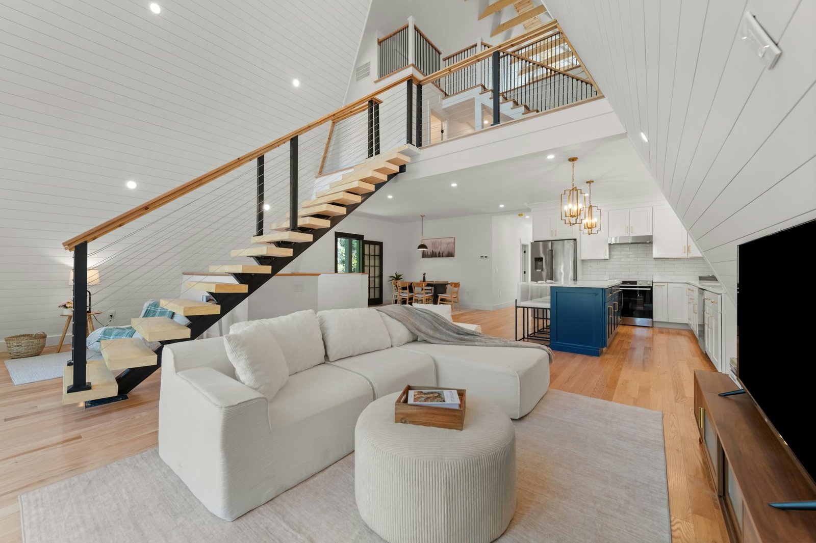 Open-plan living area with floating stairs and a blue kitchen island
