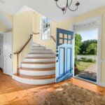 Bright entryway with a white staircase and blue front door