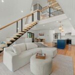 Open-plan living area with floating stairs and a blue kitchen island